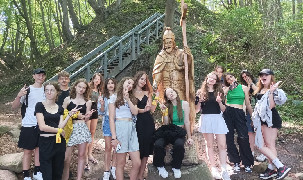 Grupa młodzieży na tle drewnianego monarchy w Jastrzębiej Górze-Lisi Jar