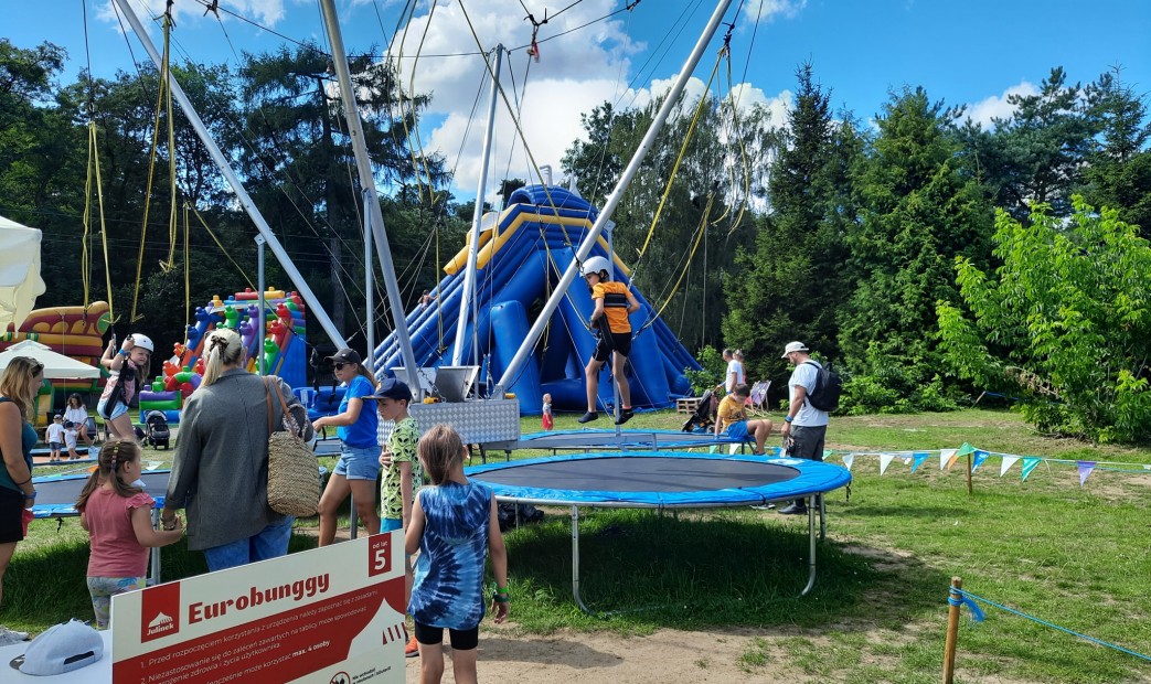 Dzieci bawiące się na trampolinach z asekuracją