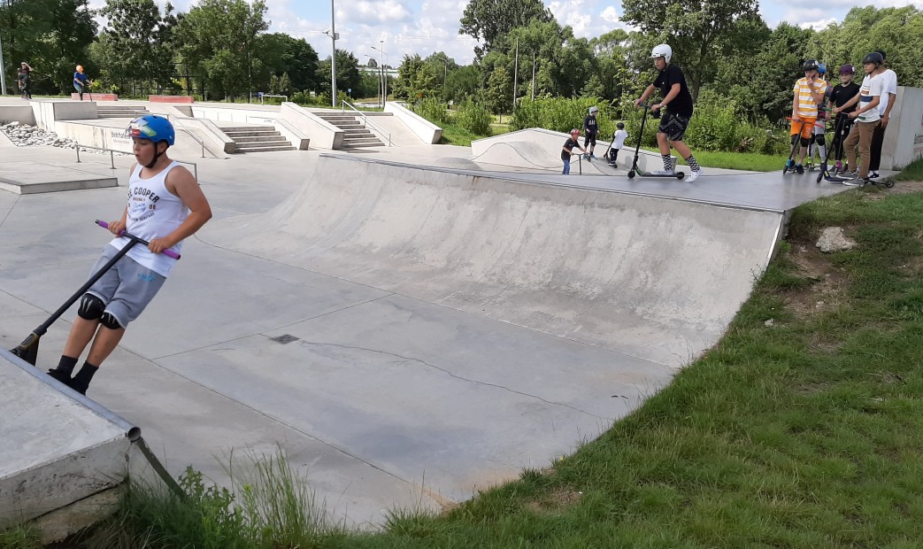 Młodzież na hulajnogach na skateparku