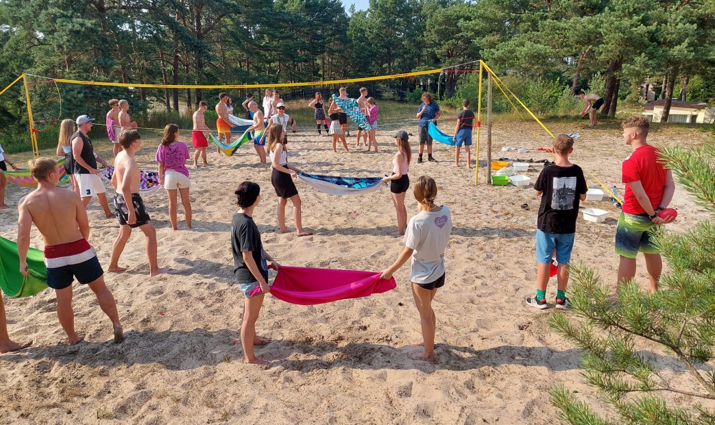Młodzież gra w siatkówke ręcznikową na plaży