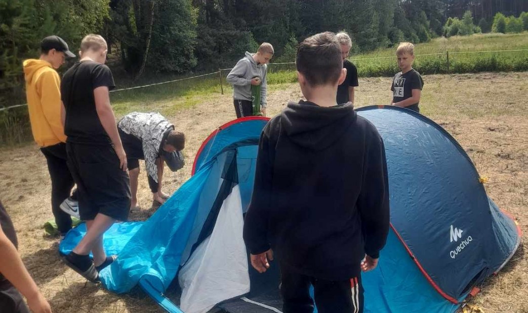 Chłopcy rozkładający namiot na biwaku